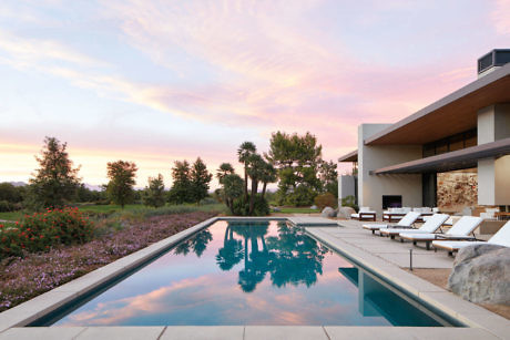 Modern house with infinity pool at sunset.