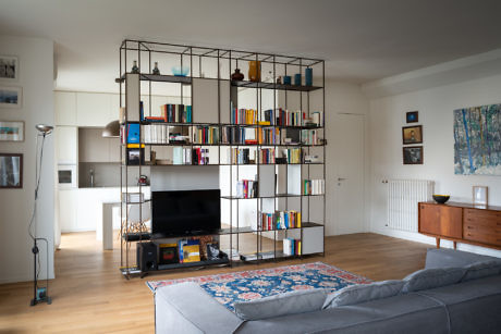 Modern living room with a large bookshelf, TV, and a gray sofa.