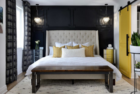 Chic bedroom with black panel wall, bright yellow door, and patterned accents