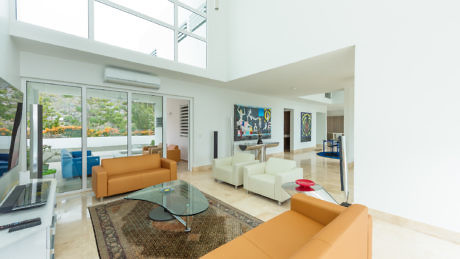 Modern living room with large windows, white walls, and brown furniture.