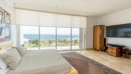 Modern bedroom with large windows overlooking the sea.