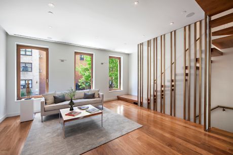 Bright living space with wooden floors and slatted staircase divider.