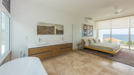 Contemporary open-plan bedroom with integrated bathroom, ocean view.