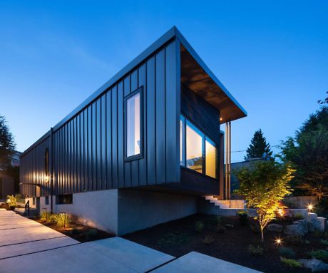 Modern house with angular design and exterior lighting at dusk.