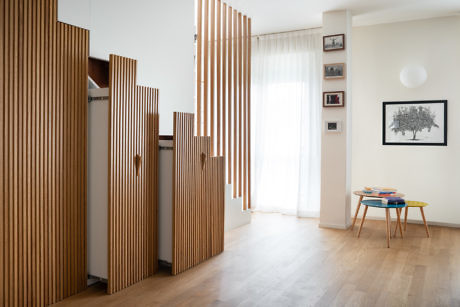 Modern room with wooden slatted partitions, hardwood floor, and minimal decor.
