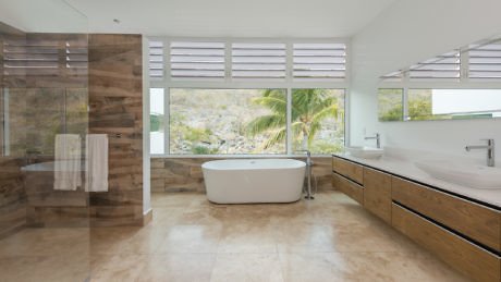Modern bathroom with freestanding tub, wooden accents, and large window.