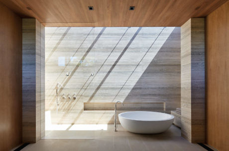 Modern bathroom with wooden walls, a white tub, and a large window.