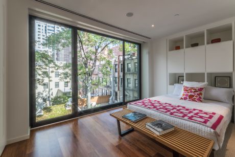 Contemporary bedroom with floor-to-ceiling window overlooking trees.