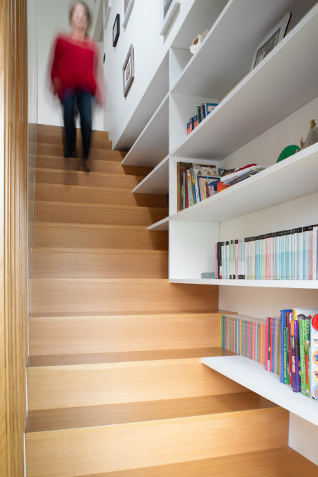Modern staircase with integrated bookshelves and blurred person descending.