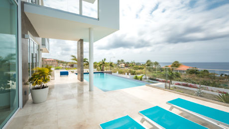 Modern house exterior with pool and sea view.
