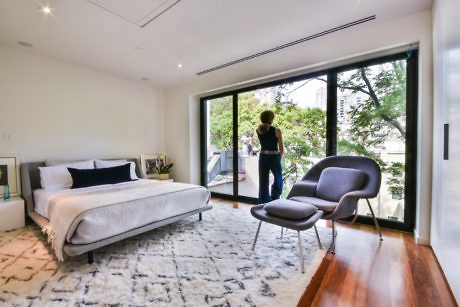 Contemporary bedroom with large window doors and hardwood floors.