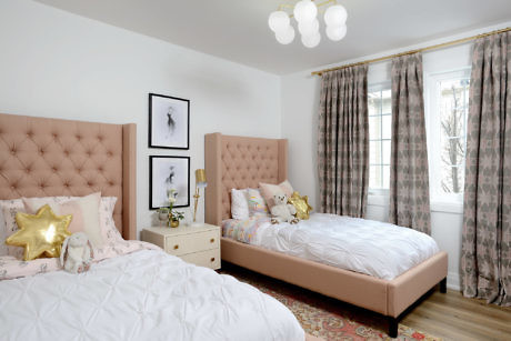 Bright bedroom with two pink tufted beds and patterned curtains.