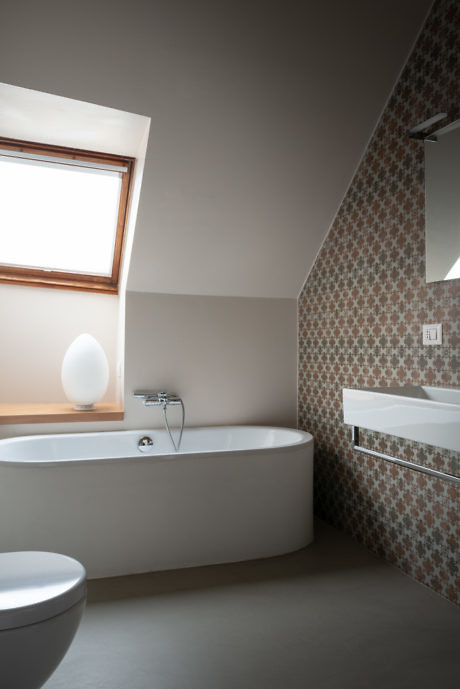 Contemporary bathroom with mosaic tile wall, white fixtures, and natural light.