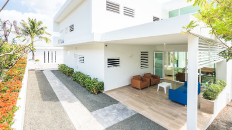 Contemporary white villa with open patio and lush landscaping.