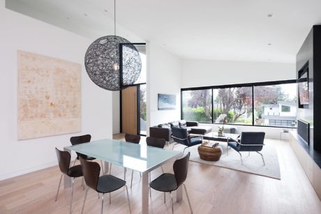 Modern dining and living room with large windows, unique pendant light, and minimalist decor