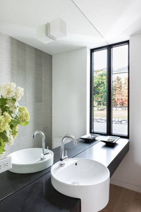 Contemporary bathroom with twin vessel sinks and tall window.
