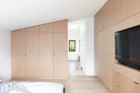 Modern bedroom with built-in wooden cabinetry and a mounted TV.