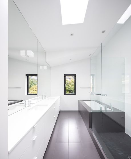 A modern, white bathroom with sleek cabinetry and glass shower enclosure.