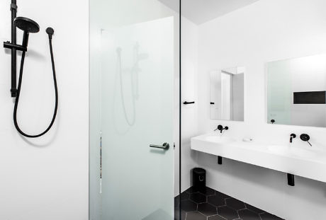 A sleek bathroom with black fixtures, glass shower, and hexagonal tiles.