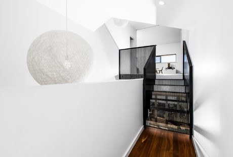 Modern stairwell with black staircase, white walls, and a large spherical pendant light
