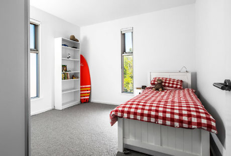 Bright bedroom with red surfboard and plaid bedding.