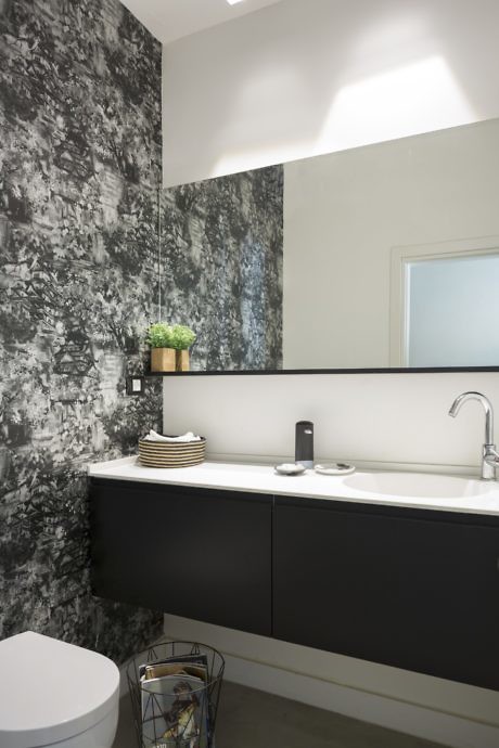 Modern bathroom with textured wall, black vanity, and round mirror.