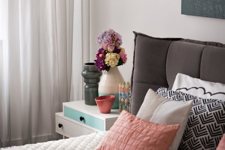 Contemporary bedroom corner with decorative pillows and flowers.