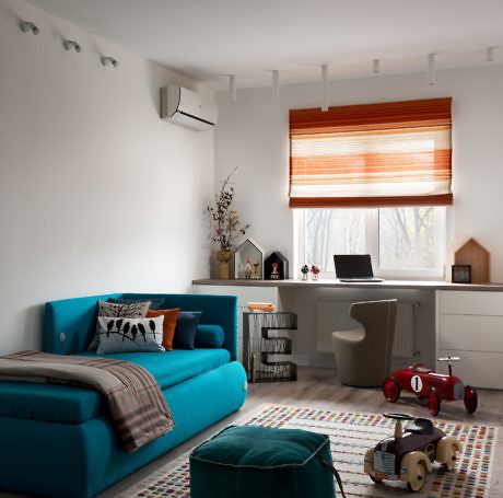 Modern room with blue sofa, colorful rug, and a window with an orange blind