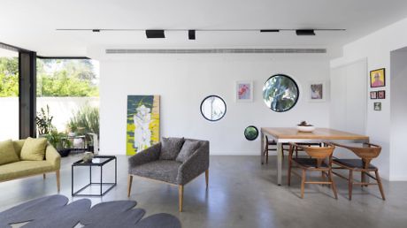 Modern living room with minimalist decor, art on walls, and wooden furniture.