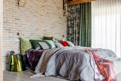 Modern bedroom with a brick wall and colorful bedding.
