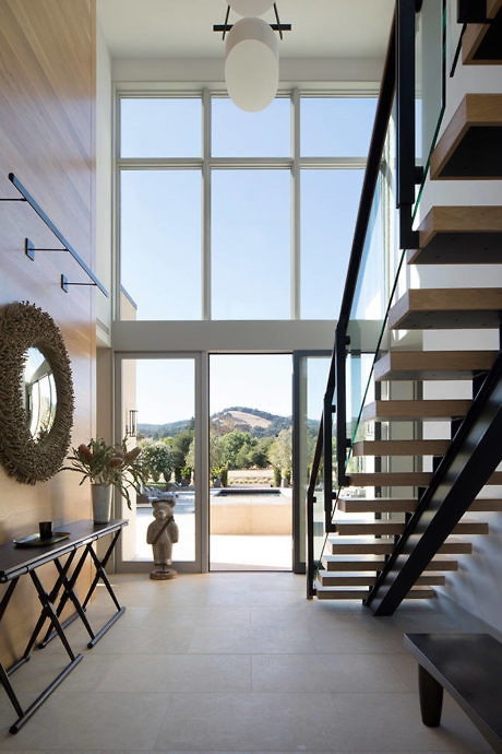 Bright entryway with high ceiling, floor-to-ceiling windows, and an open