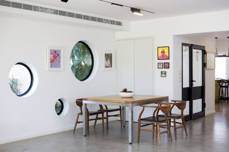 Minimalist dining room with circular wall mirrors and wooden furniture.