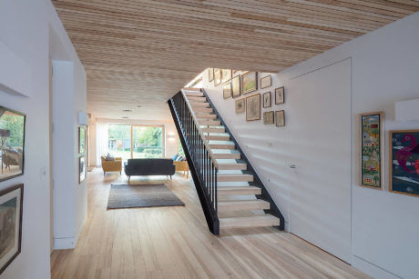 Modern home interior with wooden floors, white walls, and a black staircase.