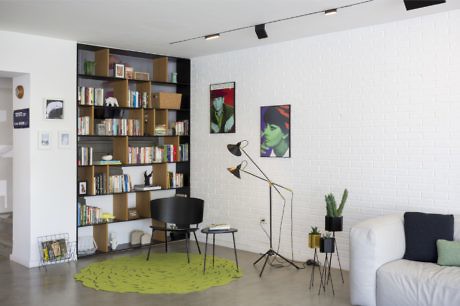 Contemporary living room with white walls, bookshelf, art, and unique floor
