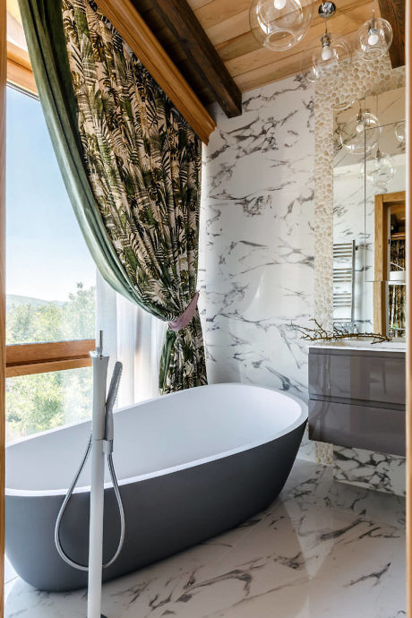 Elegant bathroom with freestanding tub, marble walls, and wooden accents.