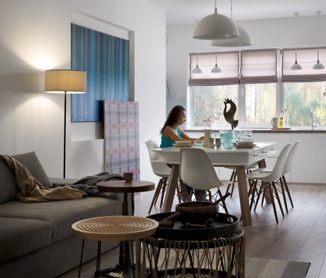 Contemporary dining area with white table, designer chairs, and a woman seated.