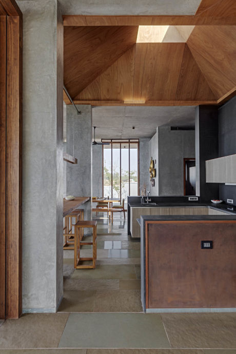 Modern kitchen interior with concrete walls and wooden ceiling.