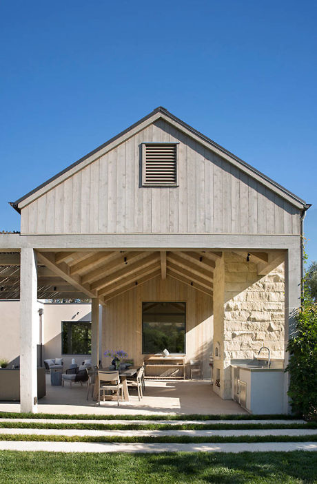 Modern barn-style house with open patio and outdoor seating.