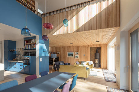 Modern living room with wooden slats ceiling and colorful hanging lamps.