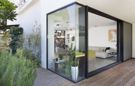 Modern home with large sliding glass doors open to a wooden deck and garden.
