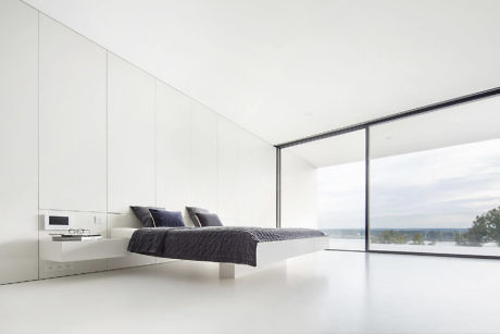 Minimalist bedroom with floor-to-ceiling window and white decor.