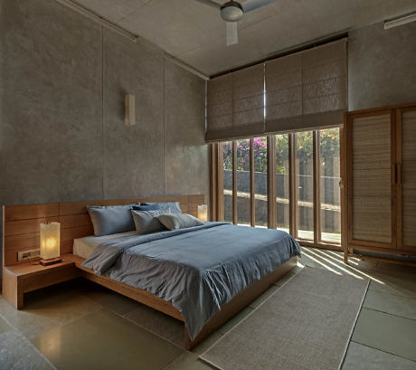 Minimalist bedroom with a large bed, gray walls, and balcony access.