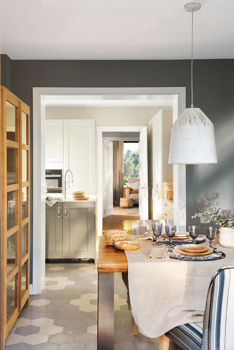 Modern dining area leading to a white kitchen with geometric floor tiles.
