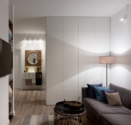 Modern living room with built-in cabinets, sofa, and decorative lighting.