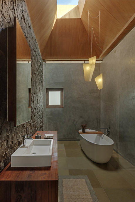 Modern bathroom with wooden accents, freestanding tub, and pendant lights.