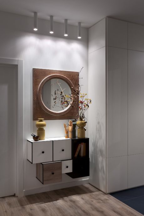 Modern entryway with decorative mirror, white cabinet, and accent lighting.