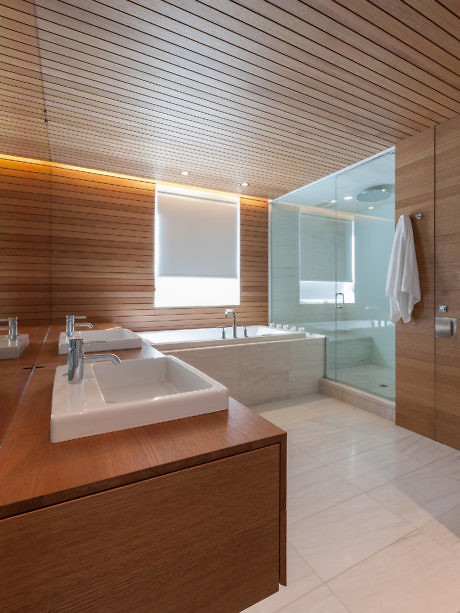 Sleek bathroom with wooden accents and glass shower.