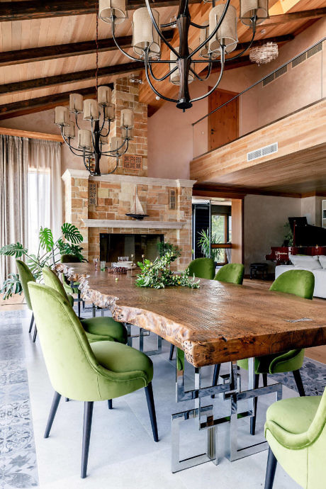 Elegant dining room with a wooden table, green chairs, and chandeliers
