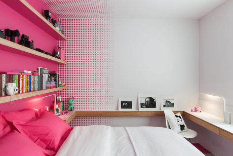 Vibrant pink-themed bedroom with dot-patterned wall and shelves.