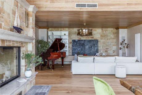 Elegant living room with grand piano and stone fireplace.